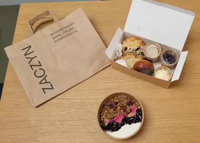 a table with two boxes of pastries and a paper bag at PLANTONIA Aparthotel in Kraków
