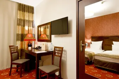 a hotel room with a bed and a desk and a bedroom at Hotel Columbus in Kraków