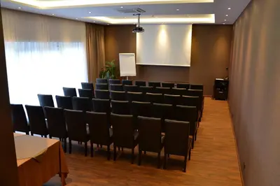 a conference room with black chairs and a screen at Hotel Columbus in Kraków