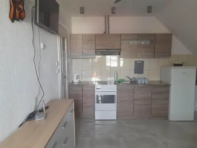 a kitchen with a white refrigerator and wooden cabinets at Mieszkanie A Łowiczki in Zator