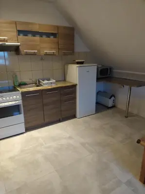 a kitchen with wooden cabinets and a white refrigerator at Mieszkanie A Łowiczki in Zator