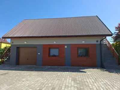 a red building with two garage doors and a staircase at Mieszkanie A Łowiczki in Zator