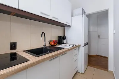 a kitchen with white cabinets and a sink at Brzozowa Apartments by Hostly in Kraków