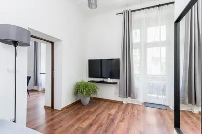 a living room with a tv and a large window at Brzozowa Apartments by Hostly in Kraków