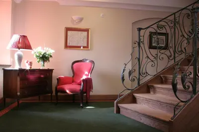 a room with a red chair and stairs and a lamp at Hotel Gródek in Kraków