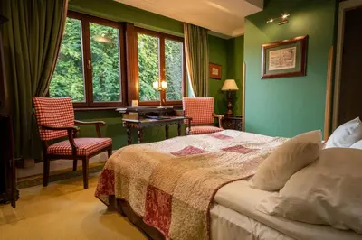 a bedroom with green walls and a bed with two chairs at Hotel Gródek in Kraków