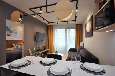 a living room with a table with plates and wine glasses at Krakowskie Malediwy by JoApart - Tauron Arena, Expo in Kraków