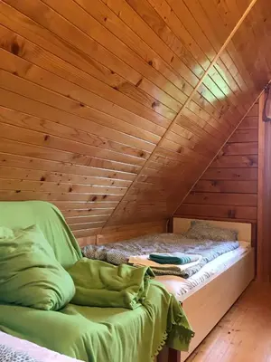 a bed in a room with a wooden ceiling at Domek letniskowy Biedówka in Limanowa