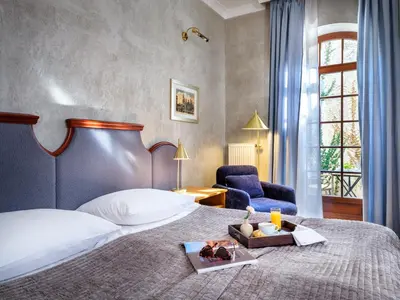 a bedroom with a bed and a desk with a television at Hotel Maltański in Kraków