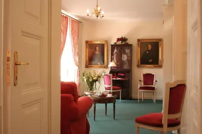 a living room with red chairs and portraits on the wall at Dom Pugetów in Kraków
