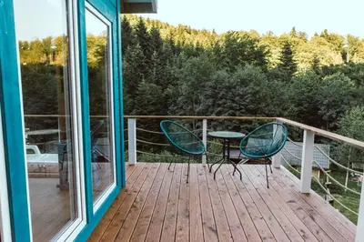 a balcony with two chairs and a table on a deck at RESETówka nr 3 - domek na odludziu z mega widokami - Lazurowe Love in Jaszczurowa