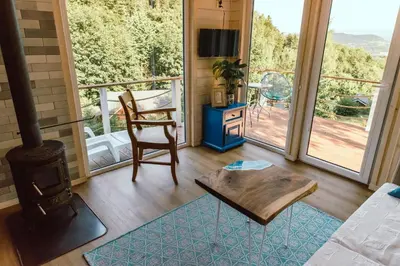 a living room with a wood stove and a balcony at RESETówka nr 3 - domek na odludziu z mega widokami - Lazurowe Love in Jaszczurowa