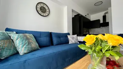 a blue couch in a living room with a clock on the wall at Chill & Fun 22 by Housine in Zator