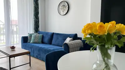 a living room with a blue couch and a vase of yellow flowers at Chill & Fun 22 by Housine in Zator