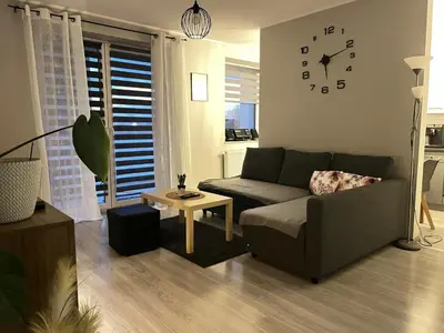 a living room with a couch and a clock on the wall at Apartament Blondynka Miasto Soli Bochnia in Bochnia