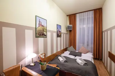 a bedroom with two beds and a desk and a window at Golden Lion Guest Rooms Szewska 19 in Kraków
