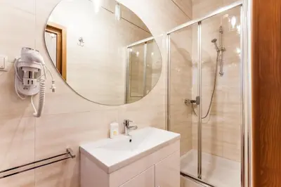 a bathroom with a sink and a shower with a mirror at Aparthotel Oberża in Kraków