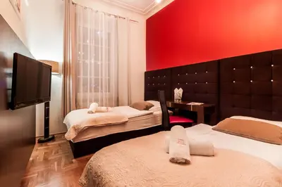 a bedroom with two beds and a flat screen tv at Aparthotel Oberża in Kraków