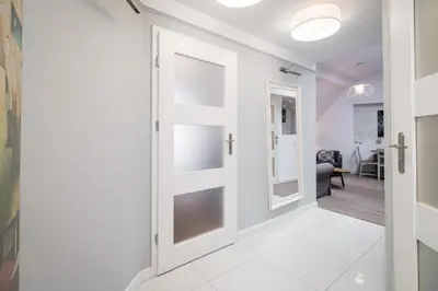 a hallway with a white door and a living room at Urban Nest Apartments Bon 11 in Kraków