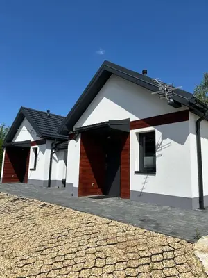 a white house with a black roof and a driveway at Nova 26 in Klucze