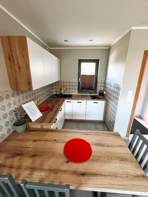 a kitchen with a wooden table and white cabinets at Nova 26 in Klucze