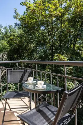 a table and chairs on a balcony with a table and cups at Old Cracow Apartment in Kraków