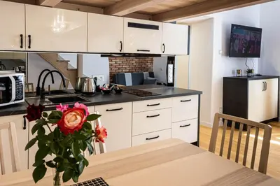 a kitchen with white cabinets and a table with a vase of roses at Old Cracow Apartment in Kraków