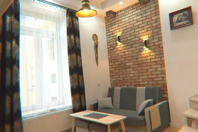 a living room with a couch and a brick wall at Old Cracow Apartment in Kraków
