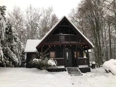 a log cabin in the snow with snow at Domek Pod Lasem in Trzciana