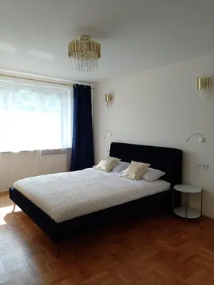 a bedroom with a large bed with a chandelier at Alexa d'Oro Rooms in Kraków