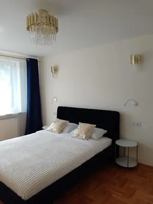 a bedroom with a large bed with a chandelier at Alexa d'Oro Rooms in Kraków