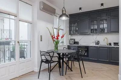 a kitchen with black cabinets and a table with chairs at Apartament w centrum Krakowa 109 in Kraków