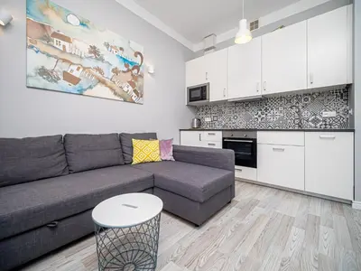 a living room with a couch and a kitchen at BARBICAN BY LANDMARK APARTMENTS in Kraków