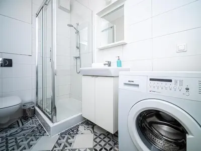 a white bathroom with a washing machine and a sink at BARBICAN BY LANDMARK APARTMENTS in Kraków