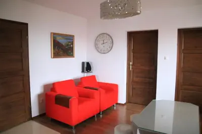 a living room with a red couch and a clock on the wall at Dom na Książkowej in Jordanów