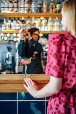 a woman standing at a bar with a drink at Hotel Apis in Kraków