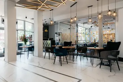a dining room with tables and chairs and windows at Hotel Apis in Kraków
