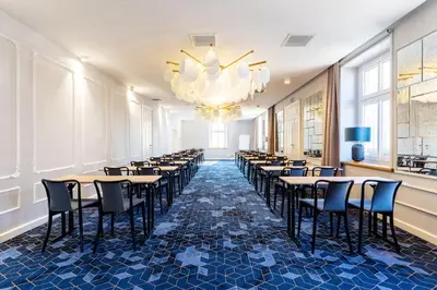 a row of tables and chairs in a room with a chandelier at Hotel Apis in Kraków