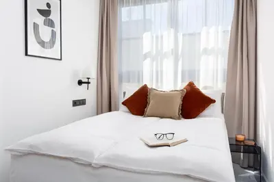 a bedroom with a white bed with a pair of glasses on it at H11 Aparthotel in Kraków