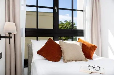 a bedroom with a white bed with a window at H11 Aparthotel in Kraków