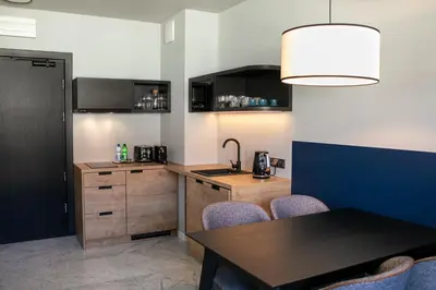 a kitchen with a table and a counter with chairs at H11 Aparthotel in Kraków