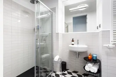 a bathroom with a glass shower and a sink at H11 Aparthotel in Kraków