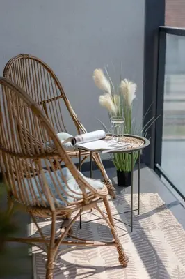 a rattan chair and a table with a glass at Apartment with Balcony & Parking Mogilska by Renters Prestige in Kraków