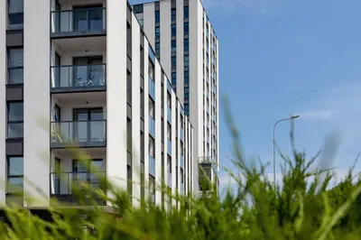 a tall white building with windows and grass at Apartment with Balcony & Parking Mogilska by Renters Prestige in Kraków