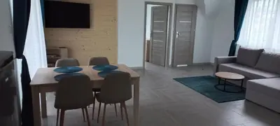 a living room with a table and chairs and a couch at Apartament Wierchy in Klikuszowa