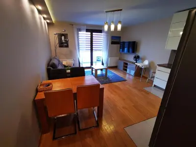 a living room with a wooden table and a dining room at Apartament Kraków Arena 20B in Kraków