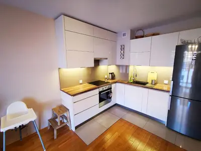 a kitchen with white cabinets and a black refrigerator at Apartament Kraków Arena 20B in Kraków