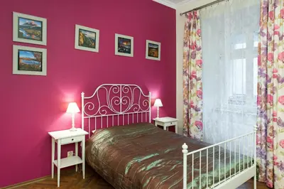 a bedroom with pink walls and a bed with two tables at Apartamenty Gołębia 3 in Kraków