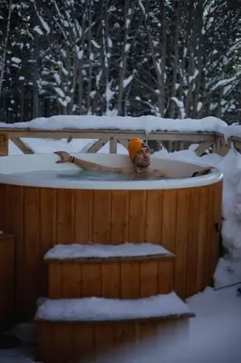 a man in a hot tub in the snow at Babiogórska Chata - dom z bali z jacuzzi i sauną in Zawoja