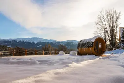 a barrel in the snow with mountains in the background at Babiogórska Chata - dom z bali z jacuzzi i sauną in Zawoja